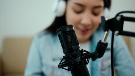 close-up condenser microphone of content creator woman host streaming his a podcast on laptop with headphones interview conversation at home broadcast studio. blogger recording voice over radio.