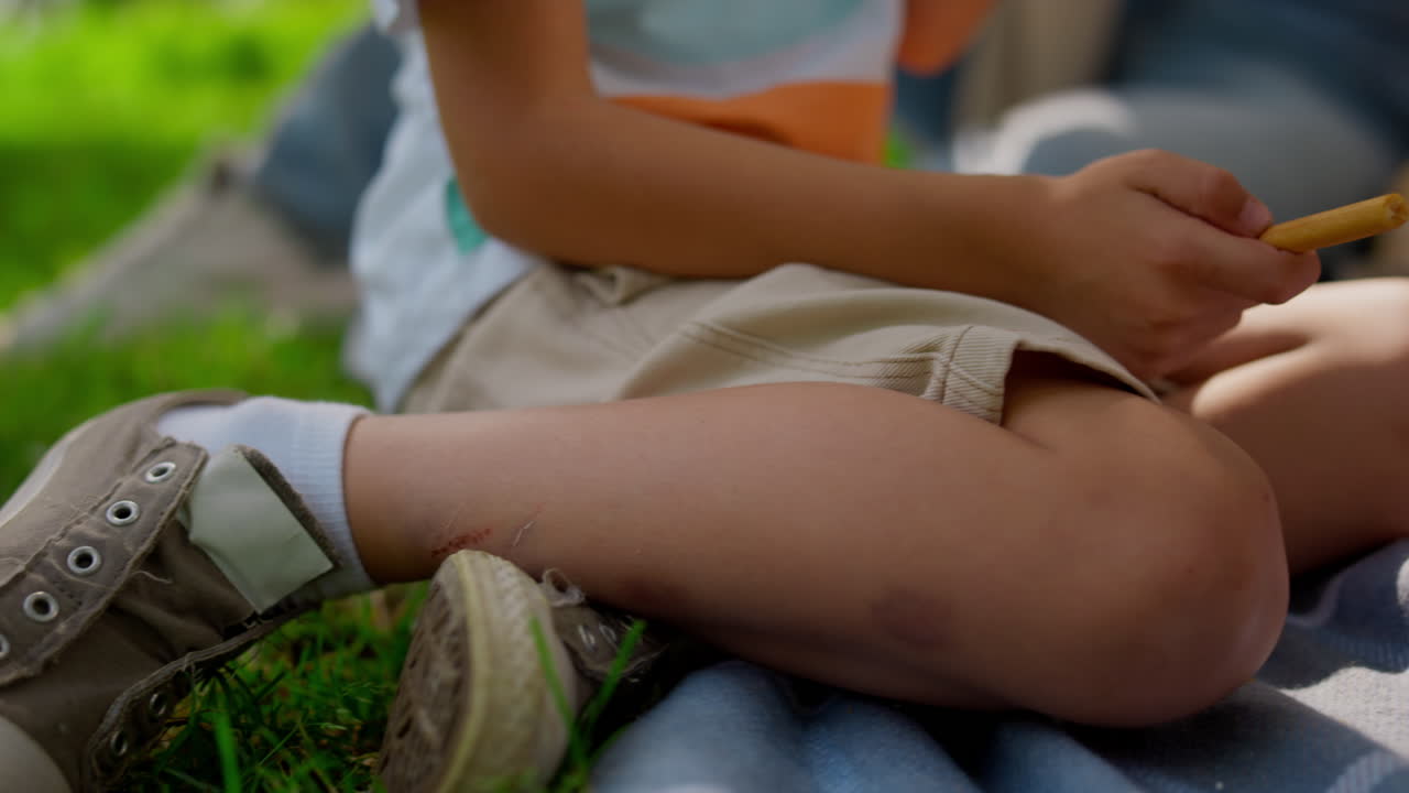 niño desconocido sentado con las piernas en una manta de cerca. niño pequeño descansando en green park.