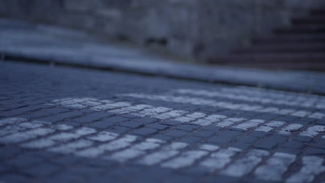 primer plano de la rueda del coche conduciendo a través del cruce de peatones en la histórica ciudad europea con pavimento de piedra cúbica durante una hora azul al anochecer
