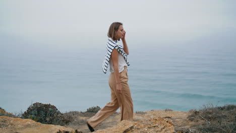 Carefree-woman-walk-coast-on-vacation-vertical.-Relaxed-girl-go-rocky-mountain