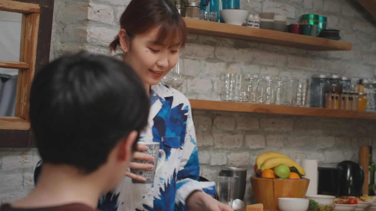 미소 짓는 아시아 여성이 두 잔의 커피를 가져옵니다.