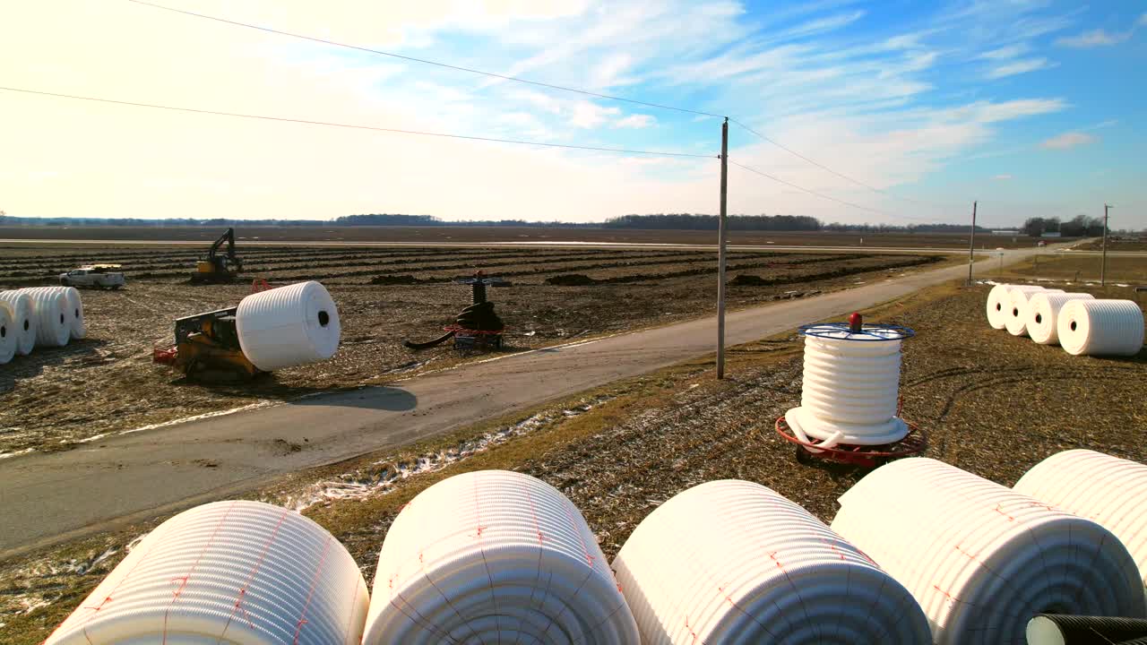 carretilla elevadora que maneja grandes bobinas industriales con tubos de plástico blanco en el paisaje rural