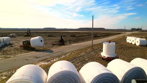 forklift handling large industrial coils with white plastic tubes in rural landscape