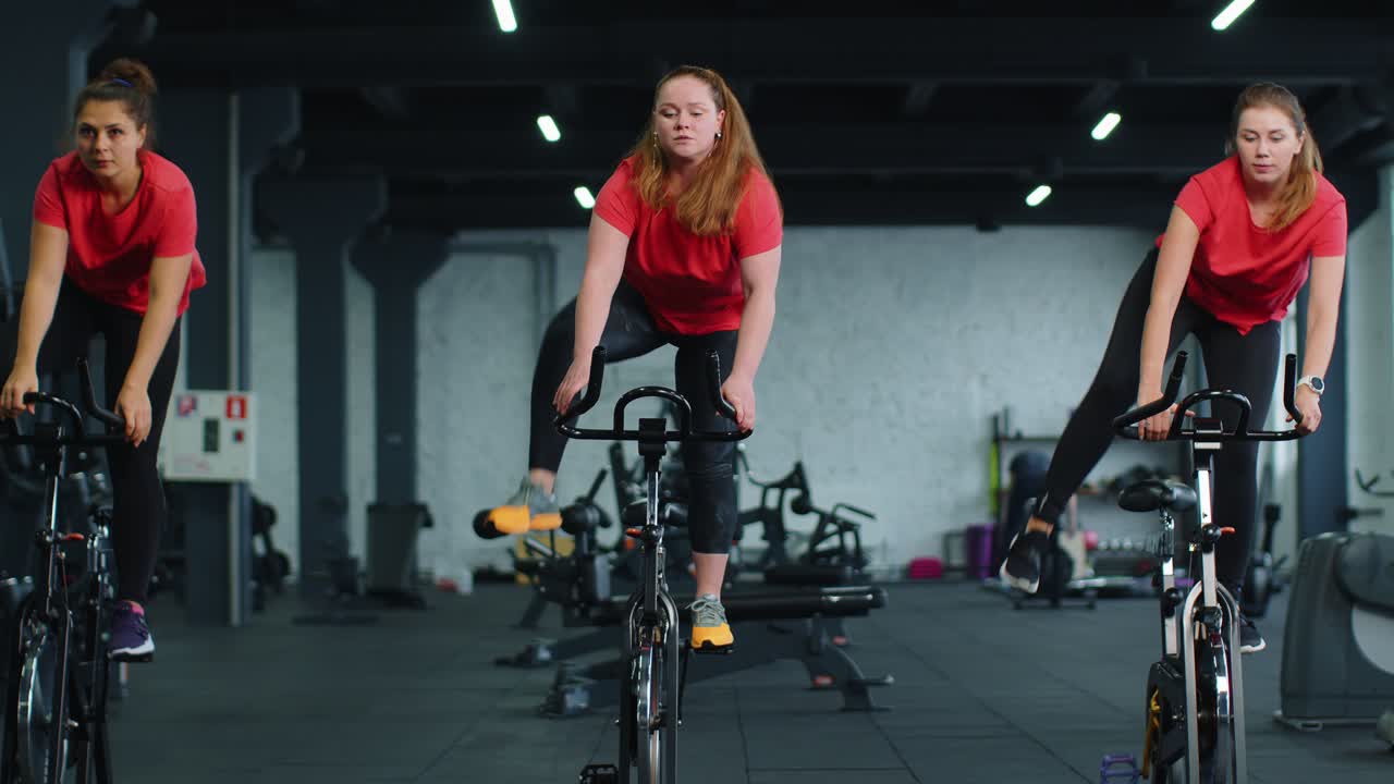 Un gruppo di ragazze esegue un allenamento aerobico, un allenamento cardio su simulatori di bicicletta, un addestramento ciclabile.