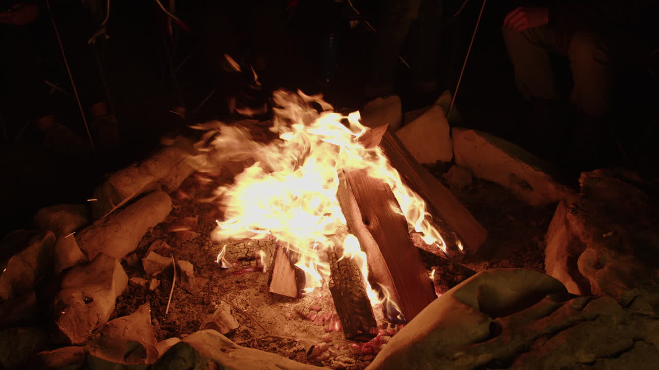 돌 고리에 있는 큰 모닥불 주위에 앉아 있는 야영자들