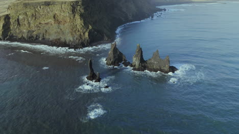 impressive rock formations of reynisdrangar near the shore of reynisfjara beach in iceland - aerial drone shot