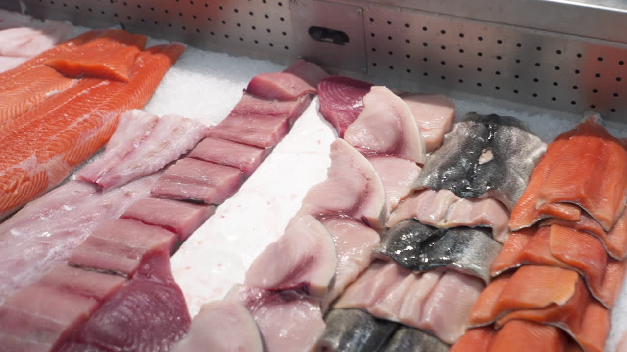Various cuts of seafood in fish market display case, slider HD