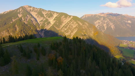 brightly lit sunny austrian woodland mountains aerial view reversing across idyllic tyrol countryside