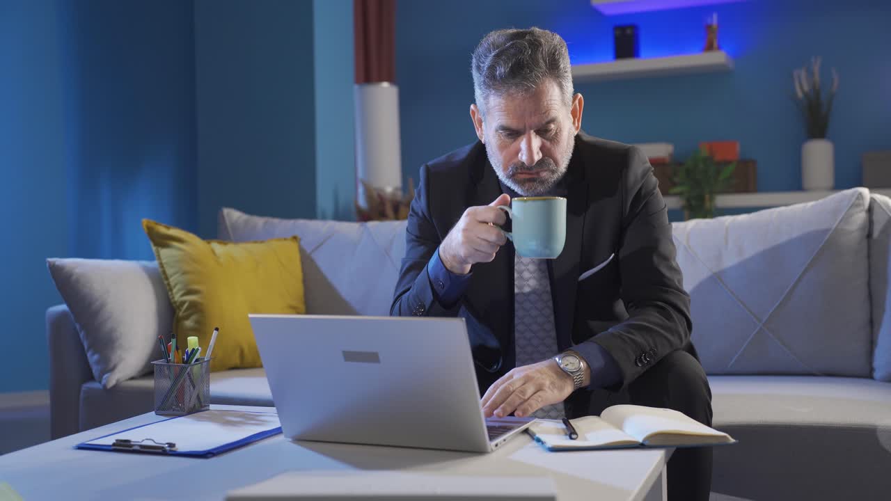 Tired and sleepy mature businessman working late at night at home.