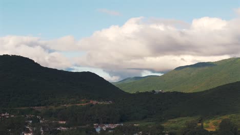 Green-forested-mountains-in-shade-and-sun,-cloud-cover,-drone-view