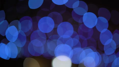 bokeh circles of blue light passing by on black background