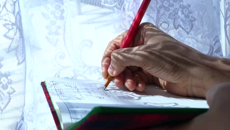 mano escribiendo en un cuaderno junto a la ventana