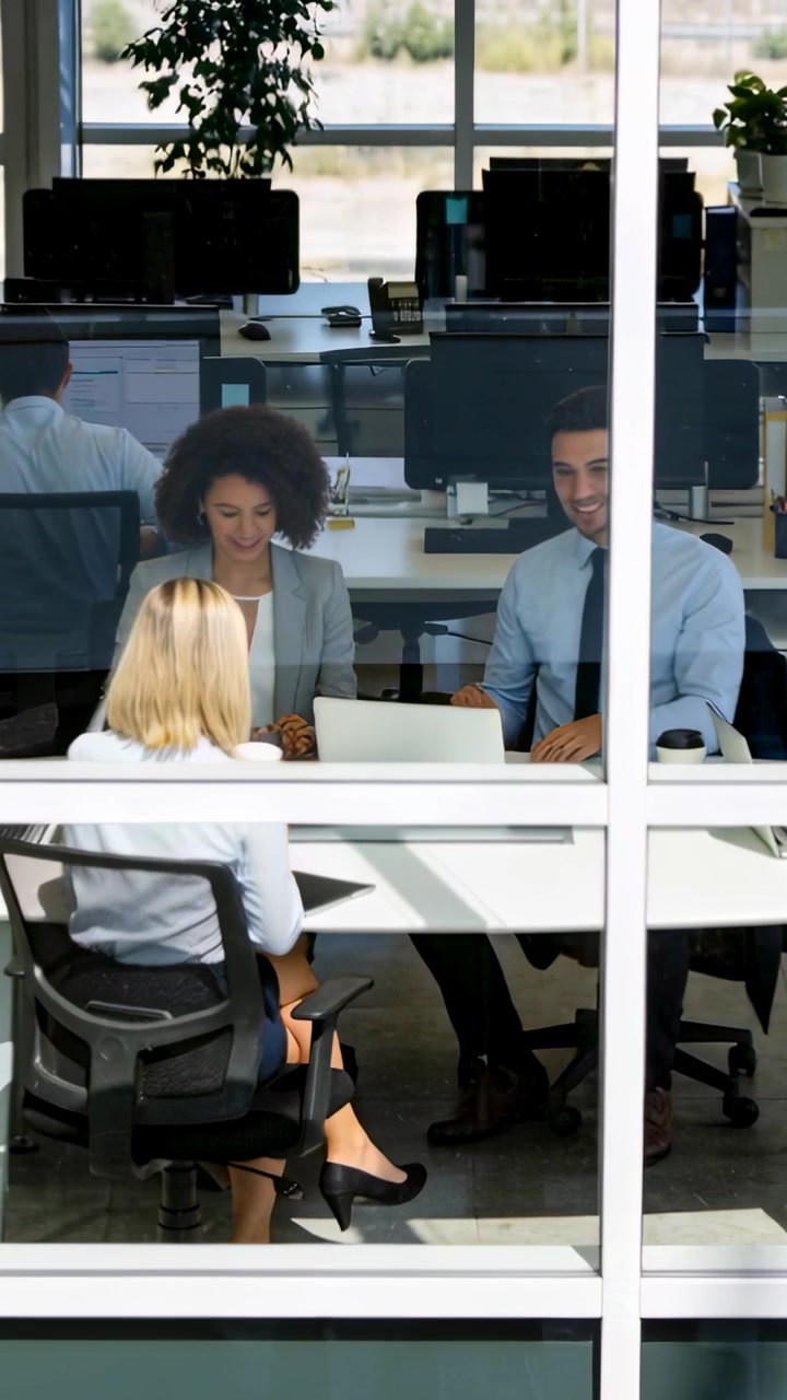 Video verticale: Bionda appoggiata che avvia una revisione a una parete di vetro, con il team che controlla un laptop in abbigliamento da lavoro.