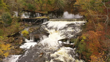 An-drone-view-over-a-waterfall-surrounded-by-colorful-fall-foliage-in-upstate-NY