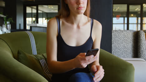 Front view of young caucasian businesswoman texting and talking on mobile phone in modern office 4k