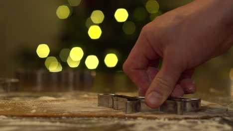 mano masculina cortando la masa de pan de jengibre aplanada con forma de corte en forma de perro