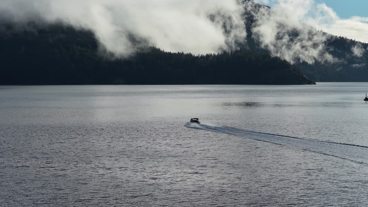 Small boat on misty water near forested Vancouver Island coast