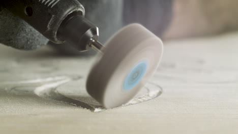 woodworker using electric engraving tool to make carved decoration on piece of wood, close-up