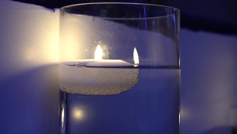 a beautiful blue candle that burns and the light makes a reflection on the wall