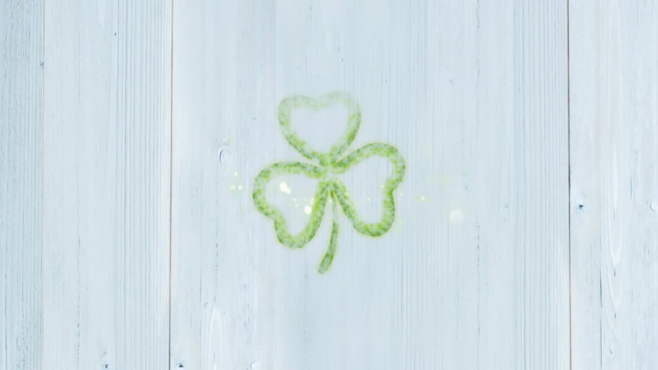 Shamrock and sparkles animation over light wooden background, festive and cheerful