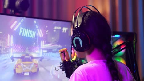 vista de atrás de cerca de la chica asiática streamer sintiéndose decepcionada falla en el juego de carreras de coches en la computadora personal. videojuego de transmisión en vivo, escritorio iluminado por luz de tira de led rgb