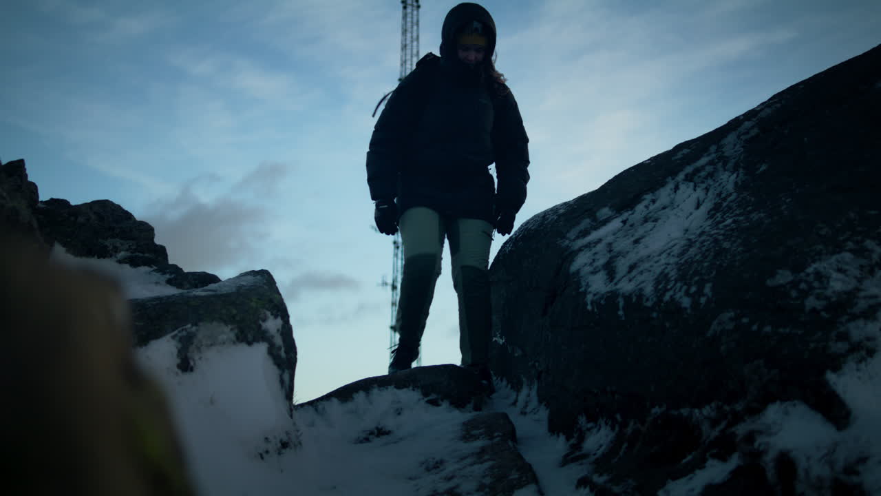Hand-held shot of a female hiker walking down from the peak of Lovstakken, Bergen