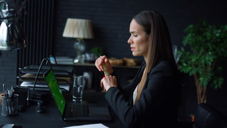 Businesswoman-video-chatting-online-on-laptop-with-green-screen-in-office