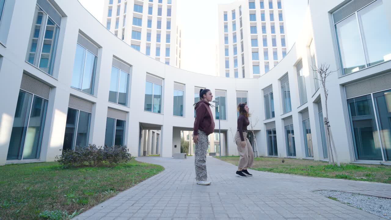 Young women dancing outside modern building