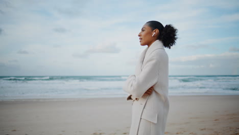 Mujer-Del-Océano-Hablando-Por-Teléfono-Con-Auriculares-Inalámbricos-En-Marcha.-Afroamericano-Disfrutar-De-La-Playa