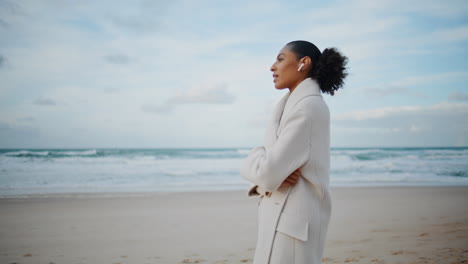 ocean woman talking phone wireless earphones on go. african american enjoy beach