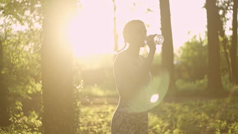 woman drinking water in the park after exercise