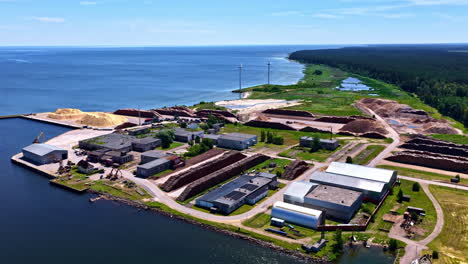 aerial view of timber processing facility with wood stacks at coastline in latvia