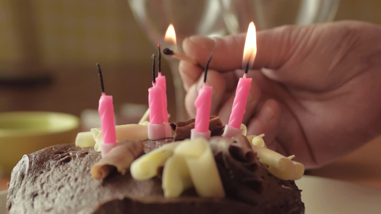 encendiendo velas a mano en pastel de chocolate con un primer plano de fósforo