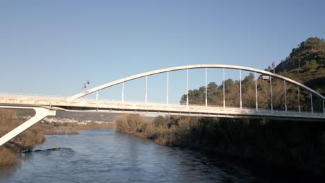 aerial shot ascending over a river and a bridge in the river miño in spain