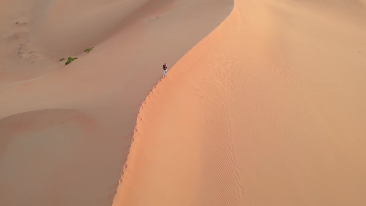 Vista aerea da drone che sorvola un giovane in piedi in cima a una duna nel deserto di Abu Dhabi, Emirati Arabi Uniti