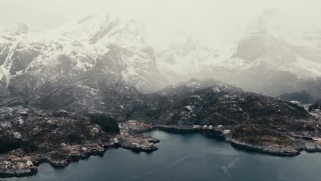 Dramatic Snow Mountains Behind Nusfjord Fishing Village In Flakstad Municipality, Norway. Aerial Drone Shot