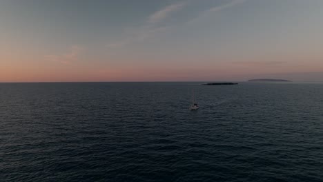 velero navegando por un mar en calma durante una hermosa puesta de sol - toma aérea