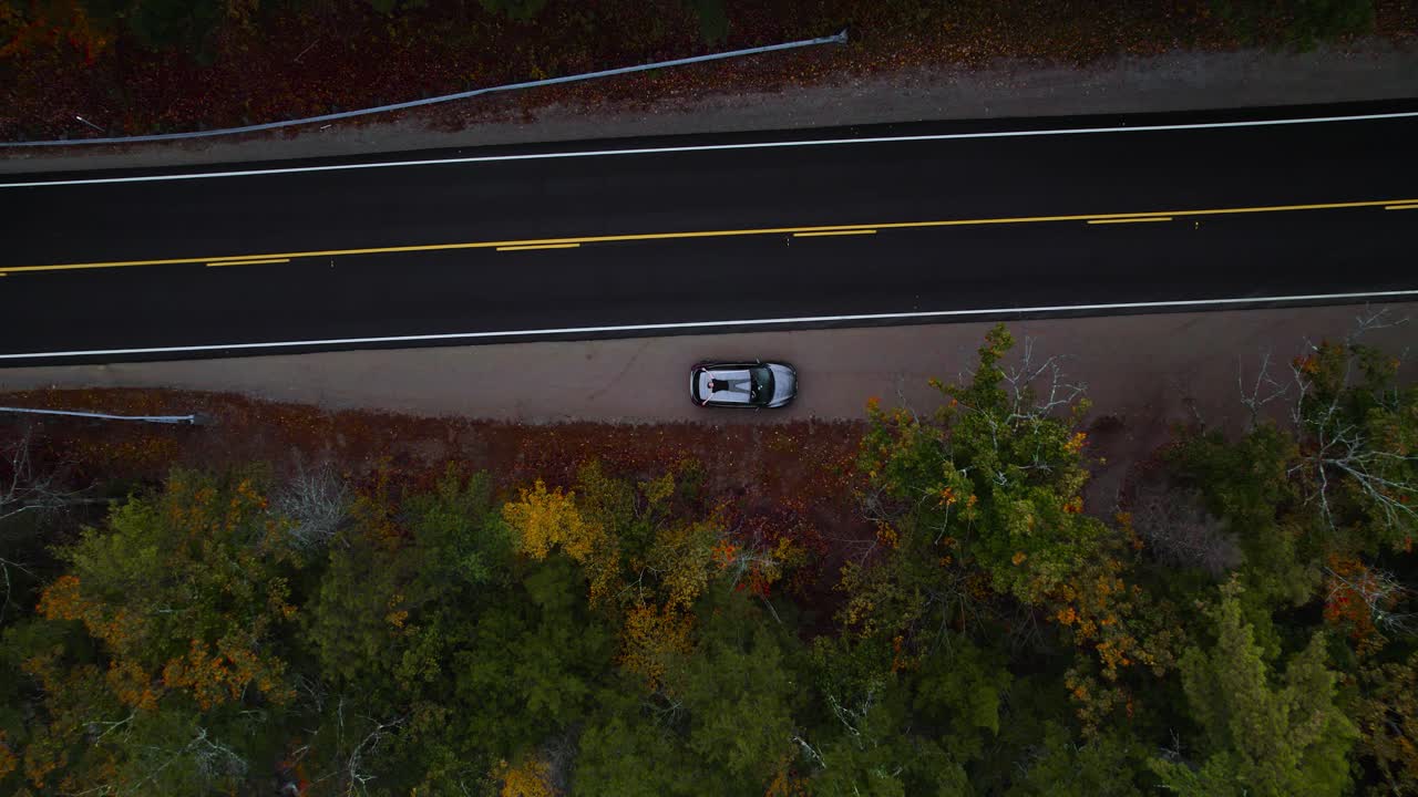 Uomo sdraiato sul tetto di un'auto nella foresta del New Hampshire, ripresa aerea ascendente