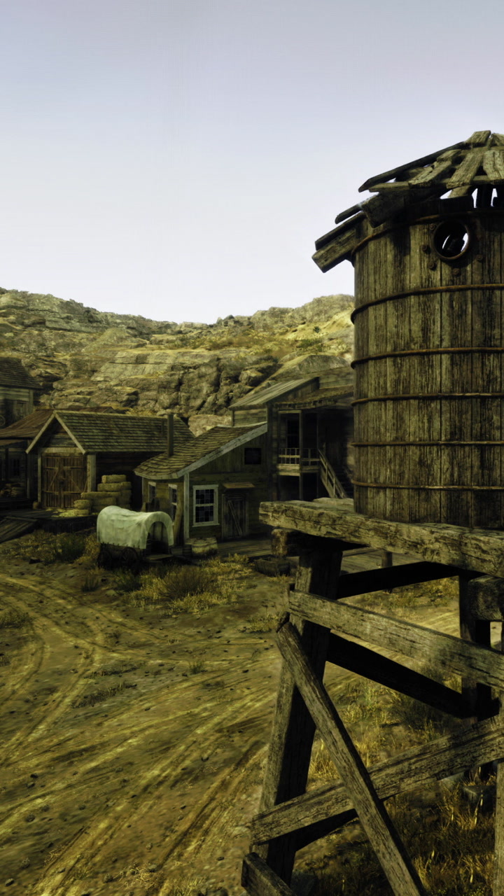 Old western town with wooden buildings and a water tower in a dry setting