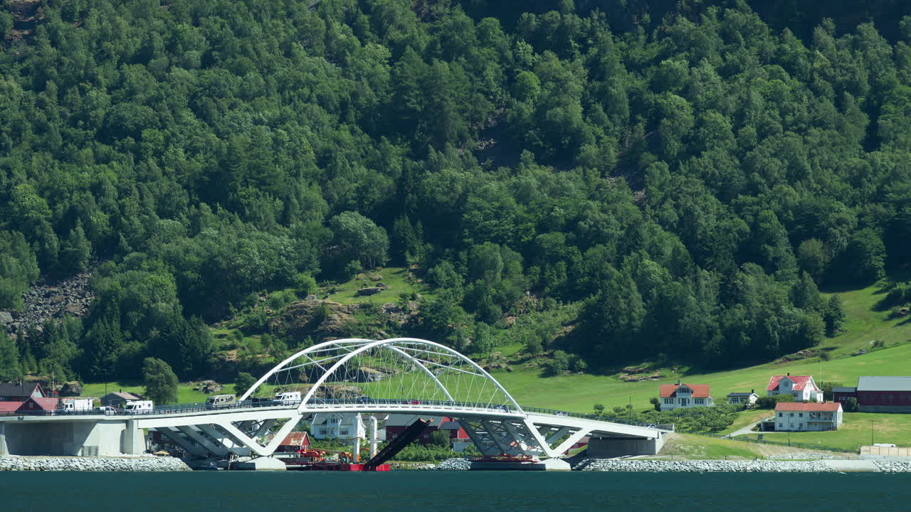 Timelapse of a busy bridge in front of green mountainside in Western Norway. Beautiful summer day.