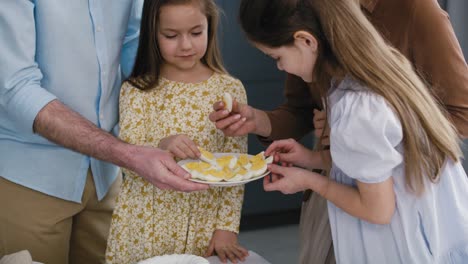 una alegre familia caucásica de cuatro personas compartiendo un huevo durante la cena de pascua.