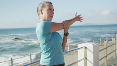 mujer mayor estirando sus brazos en un paseo marítimo