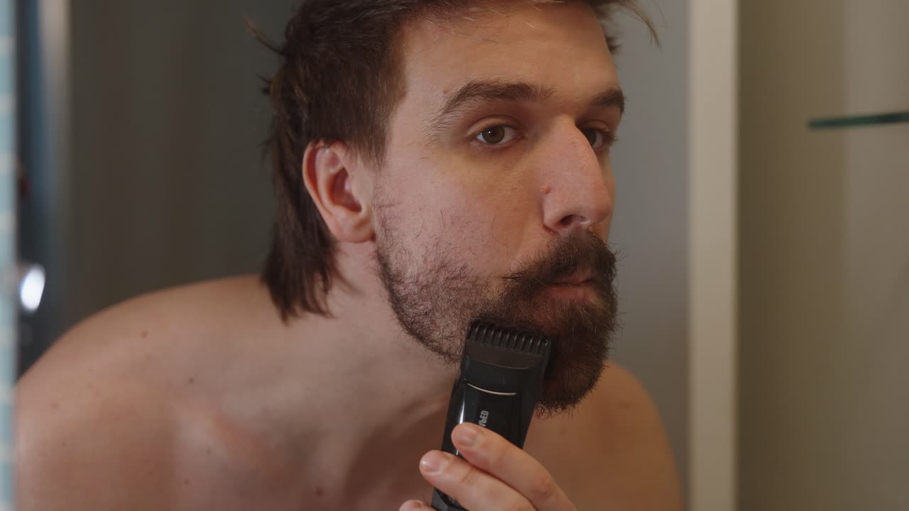 Hombre sin camisa afeitándose la barba en el baño (4k60p).