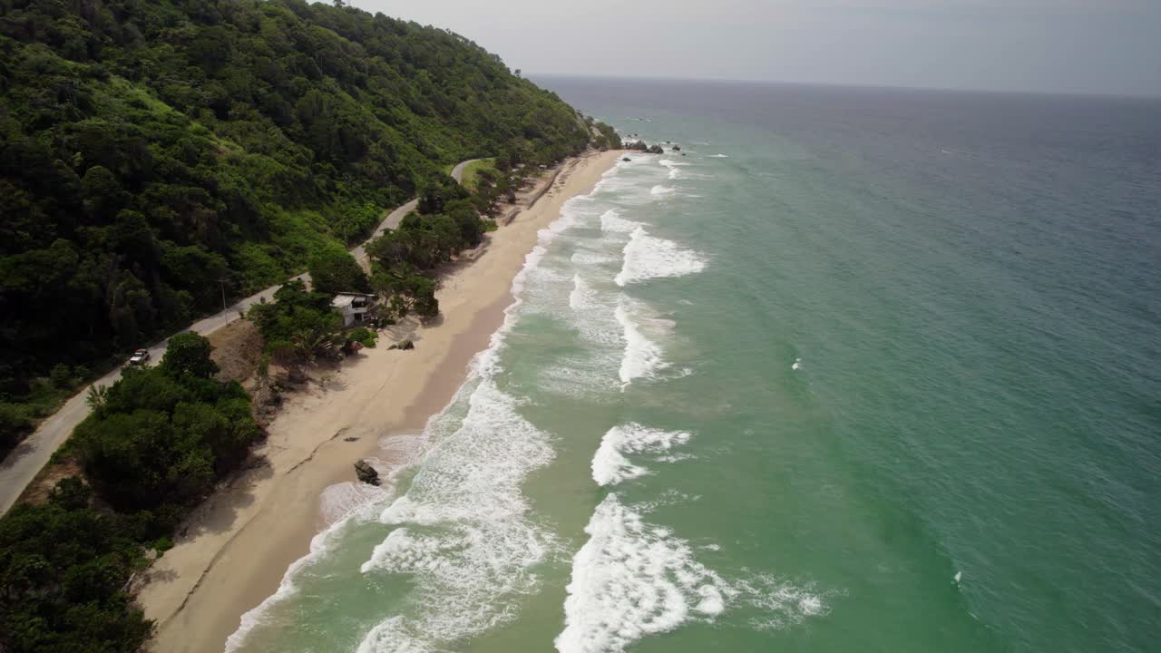 Aerial shot of Urama Beach coastline with clear turquoise waters and lush green hills