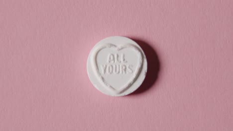 caramelo de corazón con todo tu mensaje sobre fondo rosa