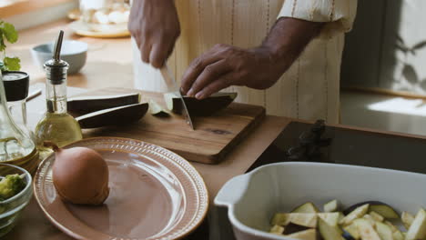 man chopping eggplant in kitchen