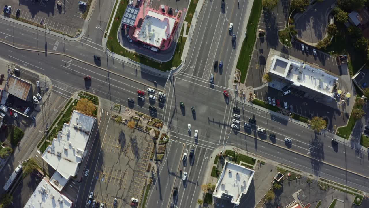 Rotating aerial drone bird's eye top view shot of a busy road intersection in the middle of a business center surrounded by buildings on a sunny fall day in Salt Lake county, Utah