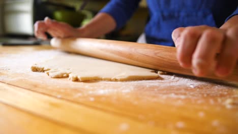 Hands-rolling-dough-with-rolling-pin-on-floured-surface