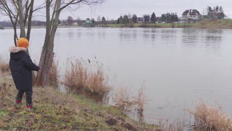 magnetic fishing from river, boy throwing magnet on rope to water, wide angle view