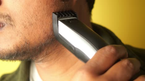 hombre recortando su barba con una navaja eléctrica